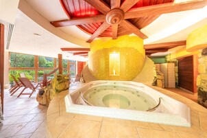 A spa area with a hot tub, wooden ceiling beams, stone walls, and a view of the outdoors.