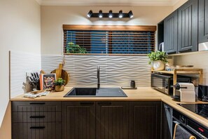 A modern kitchen with a black sink, wooden countertop, and dark cabinets.