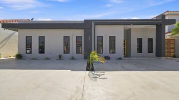 A modern two-story building with a flat roof, multiple windows, and a concrete driveway.