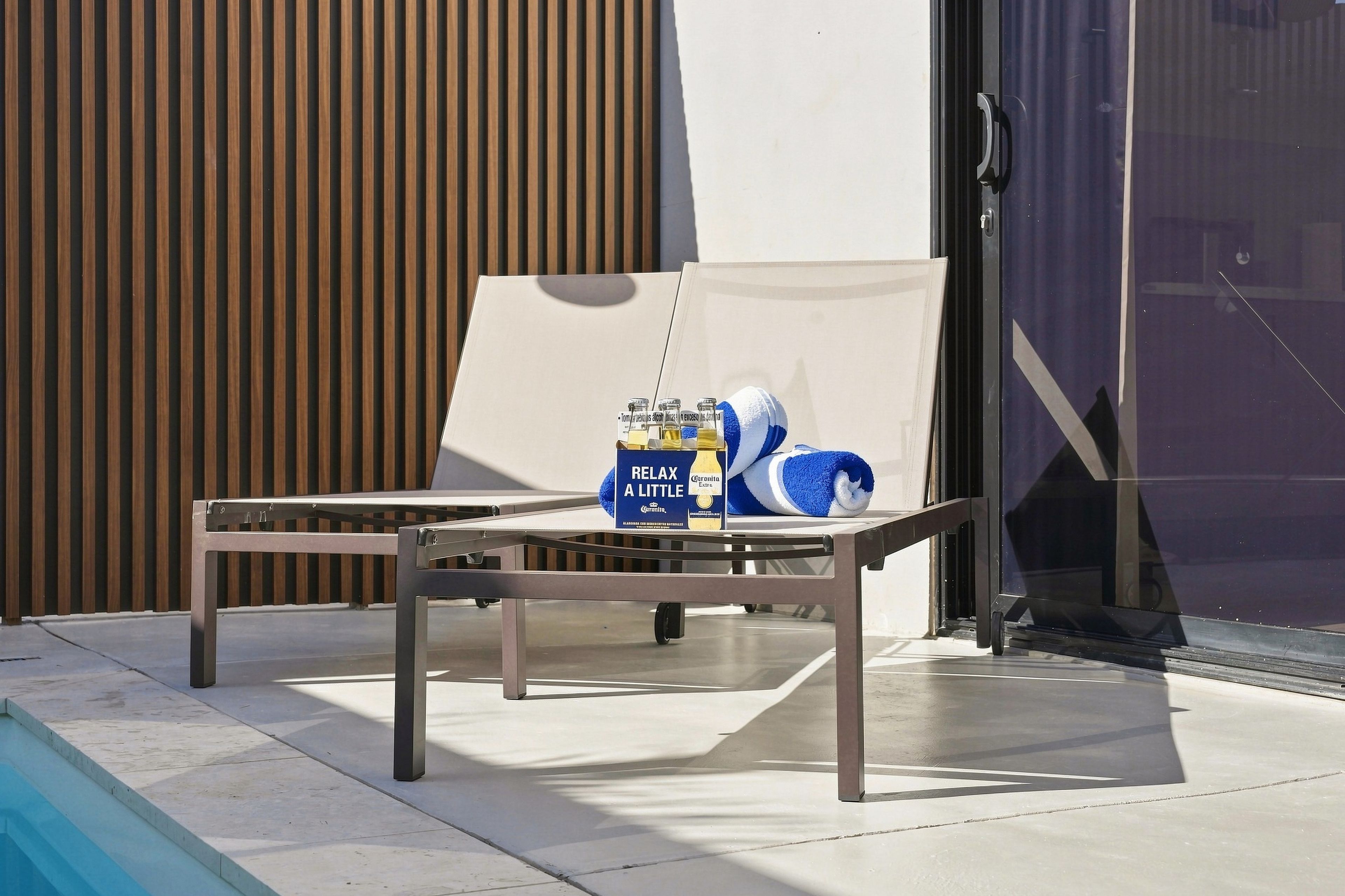 A metal table with a towel and Corona beer bottles outside a building.