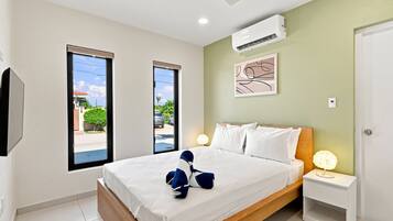 A hotel room with a bed, a nightstand, a wall-mounted air conditioner, and a window with a view of the street.