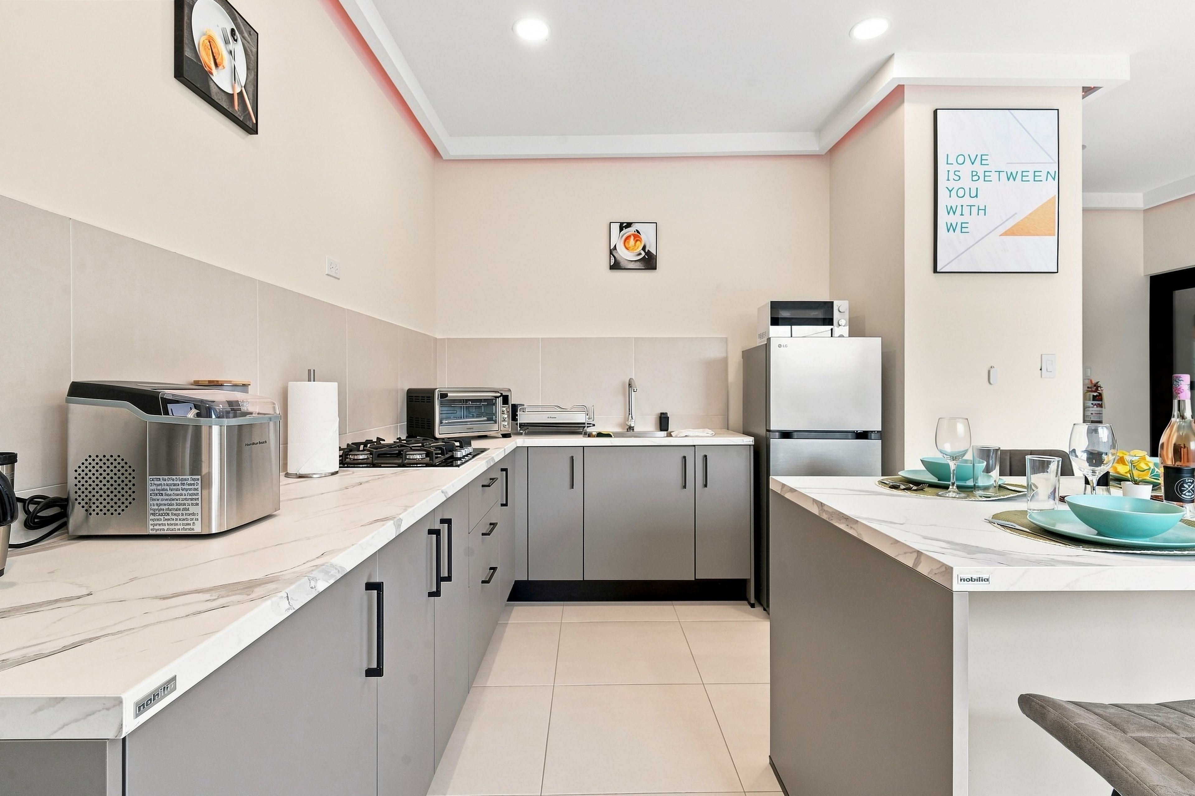 A modern kitchen with grey cabinets, a built-in oven, a microwave, and a refrigerator.