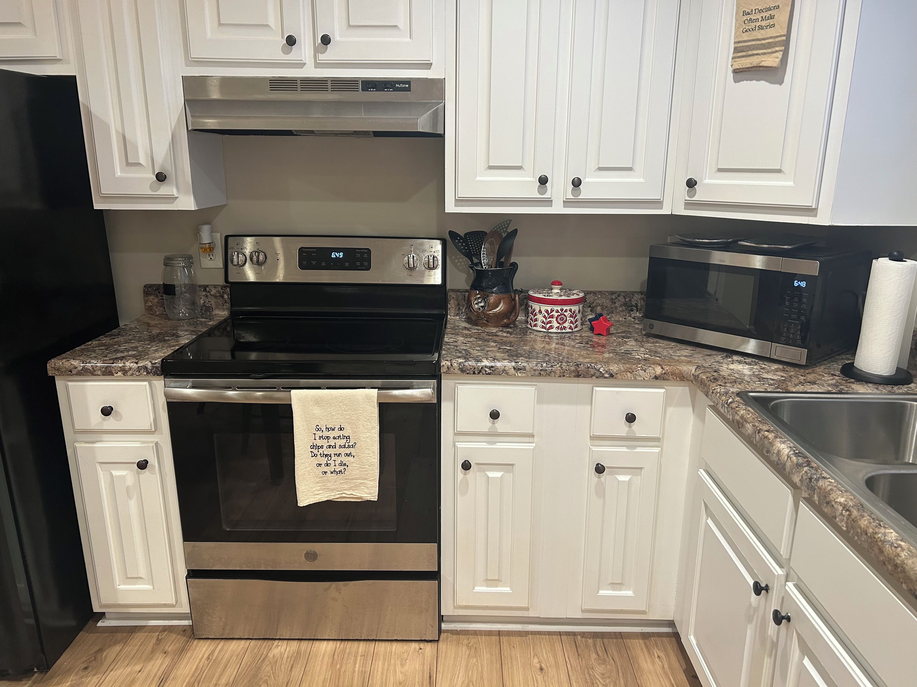 A kitchen with white cabinets, a stainless steel oven, a microwave, and a granite countertop.