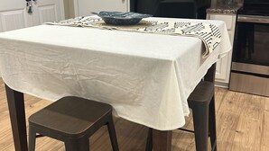 Et køkken med et bord dækket til to personer, et sort køleskab og trægulv.