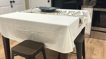 Una cocina con una mesa para dos, un refrigerador negro y piso de madera.