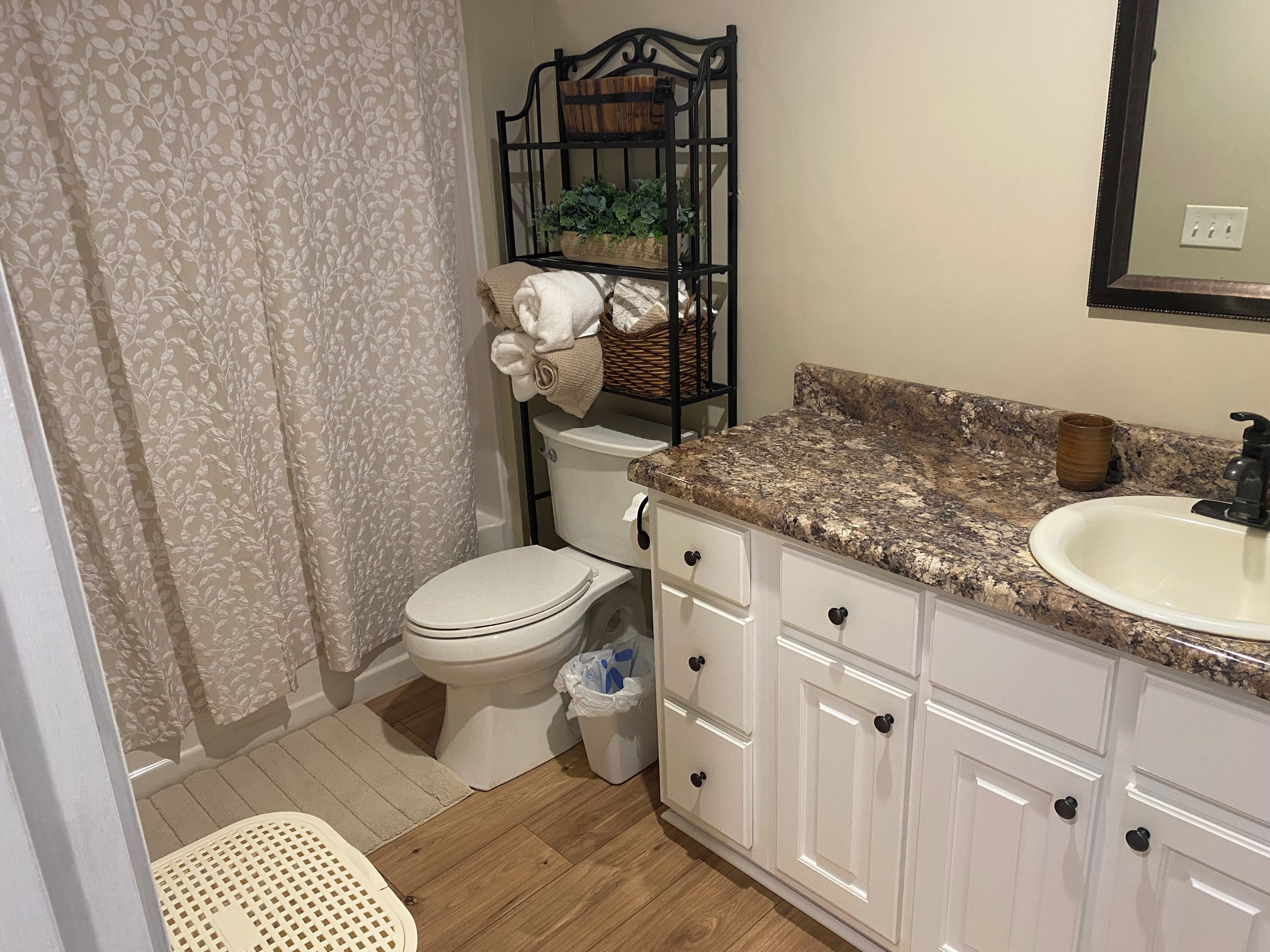 Un baño con inodoro, lavabo, espejo y cortina de ducha.