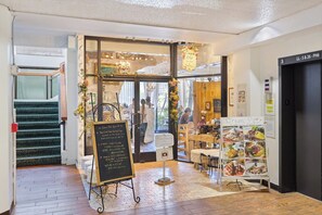 A restaurant interior with a chalkboard menu, a cream pot sign, and a staircase leading to an upper level. - Waikiki Studio | Pool + Beach Gear | City Views (Honolulu)