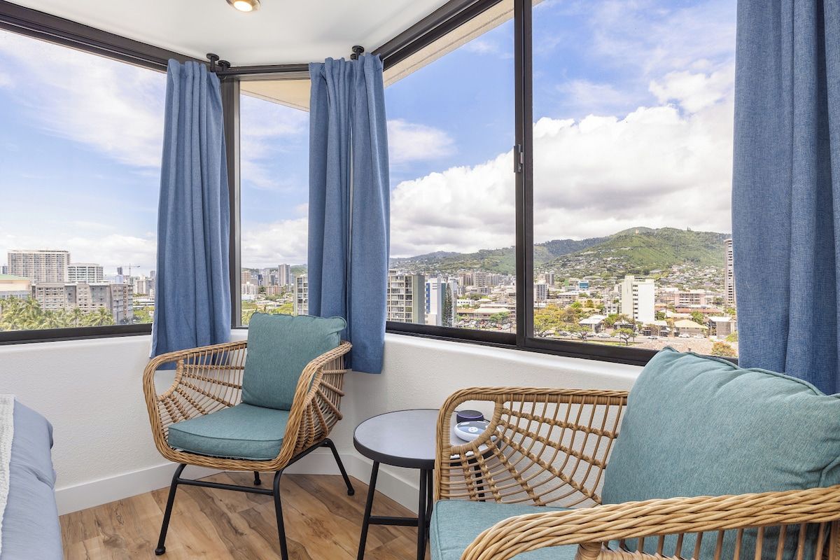 A balcony with wicker furniture and a view of a cityscape.