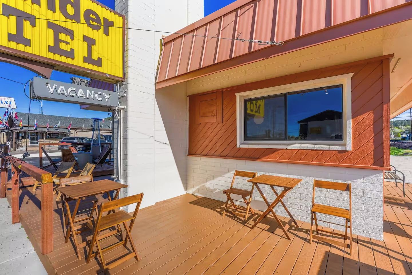 An outdoor seating area with wooden tables and chairs, a visible 'VACANCY' sign, and a building with a window displaying '401'.