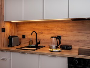 Una cocina con encimera de madera, cafetera, hervidor y tostadora.