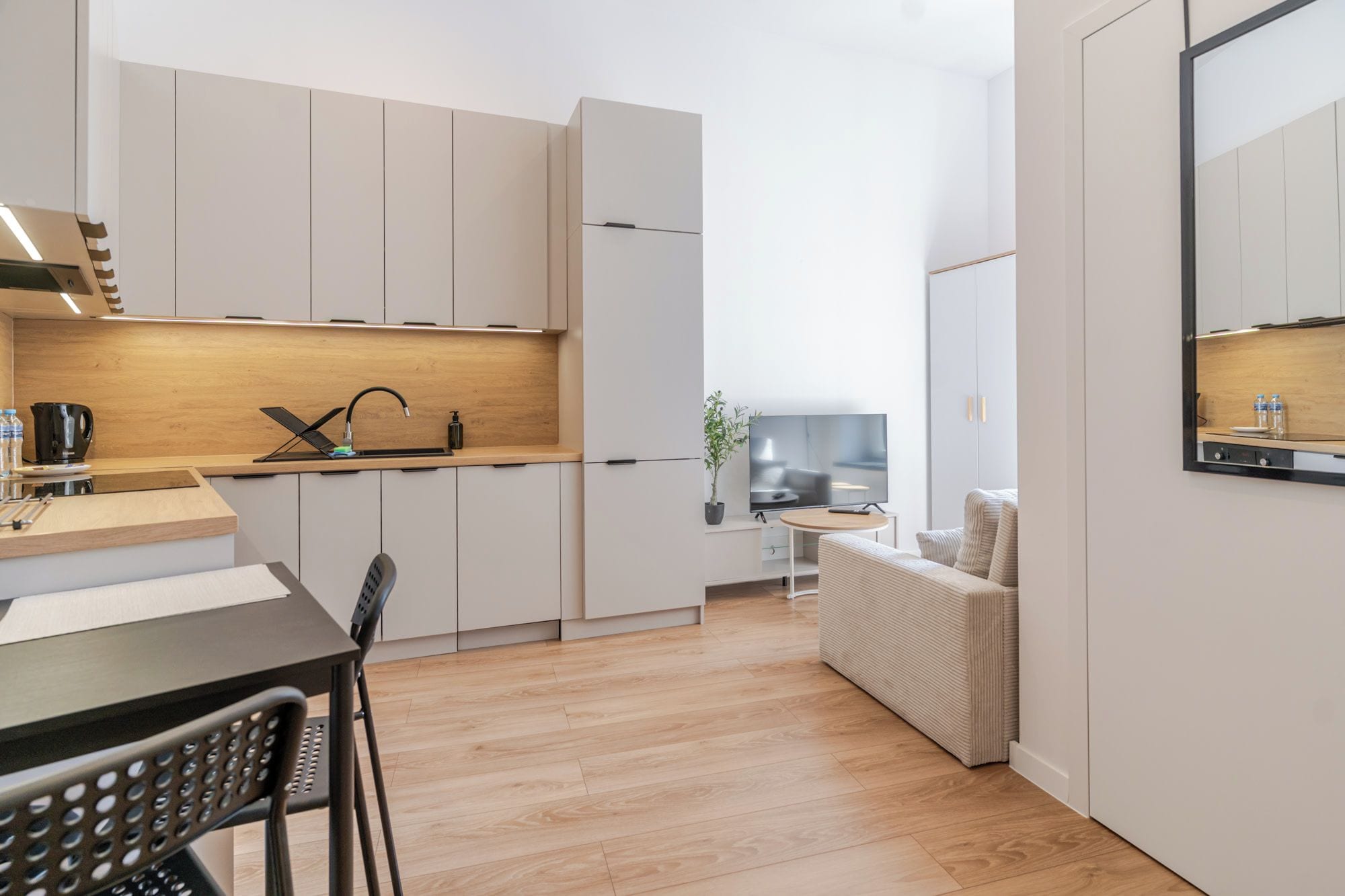 A modern kitchen with white cabinets, a wooden countertop, and a dining area with a table and chairs.