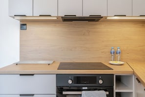 A modern kitchen with wooden cabinetry, a black countertop, and a built-in oven.