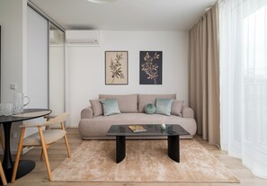 A modern living room with a sofa, a coffee table, and a dining area with chairs. - Browary Warszawskie Boutique Studio (Warszawa)