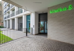 A modern building entrance with a brick wall and a neon sign. - Browary Warszawskie Boutique Studio (Warszawa)