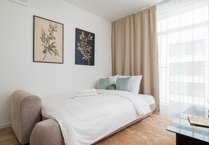 A modern bedroom with a bed, a chair, and two framed botanical prints on the wall. - Browary Warszawskie Boutique Studio (Warszawa)