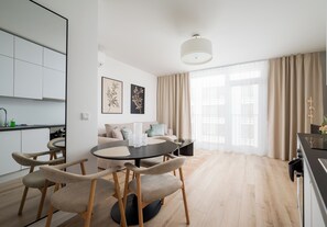 A modern living space with a dining area, kitchen, and a large window with curtains. - Browary Warszawskie Boutique Studio (Warszawa)