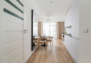A modern kitchen with a dining area, wooden flooring, and a large mirror on the left wall. - Browary Warszawskie Boutique Studio (Warszawa)