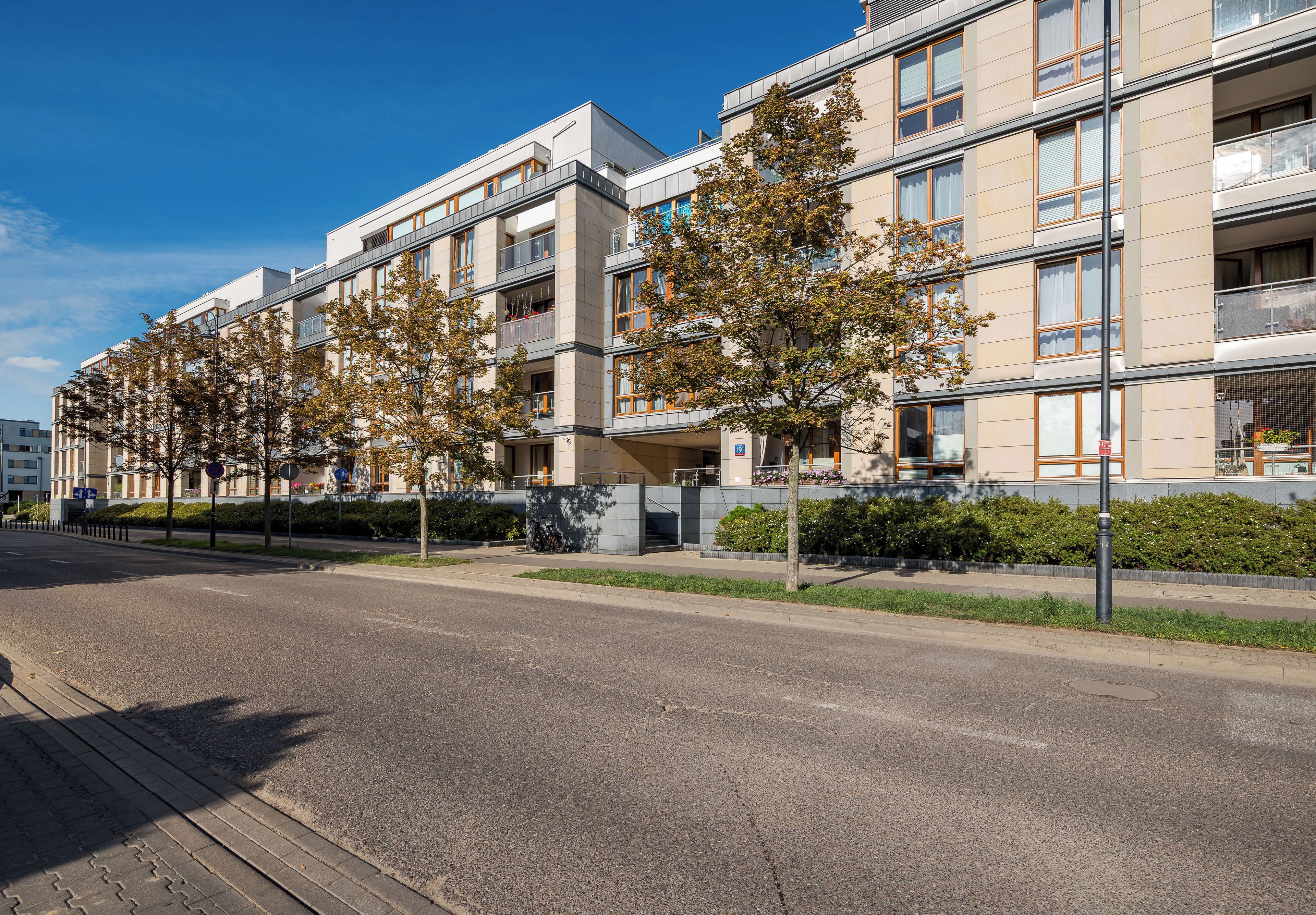Un immeuble résidentiel moderne à plusieurs étages, doté de balcons et surplombant un ciel dégagé.