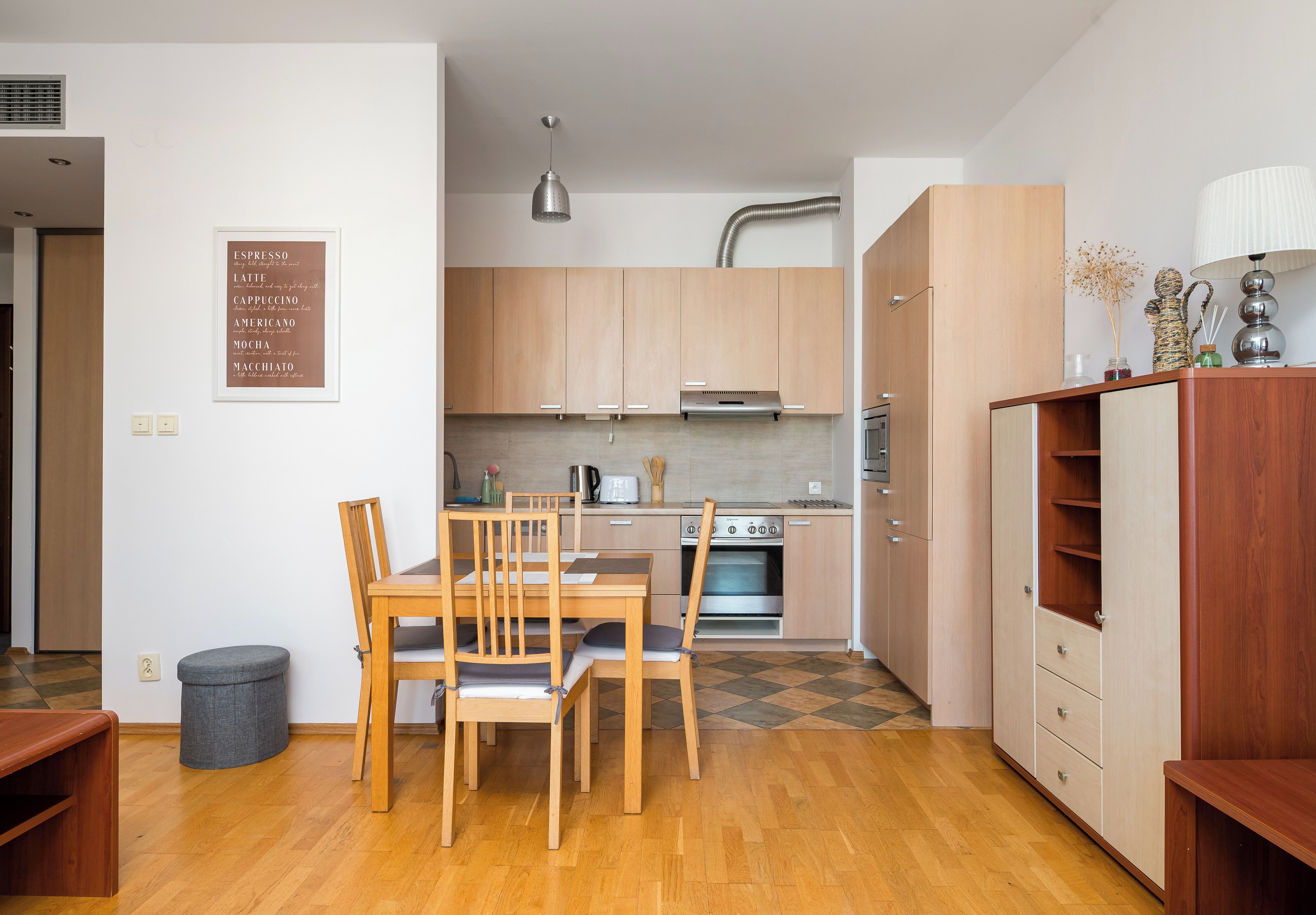 Une cuisine moderne avec des meubles en bois, une table à manger avec des chaises et une machine à café.
