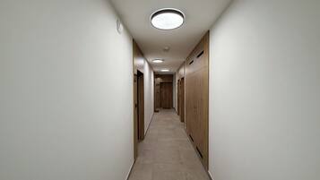 A hallway with lockers on both sides, a tiled floor, and recessed lighting.