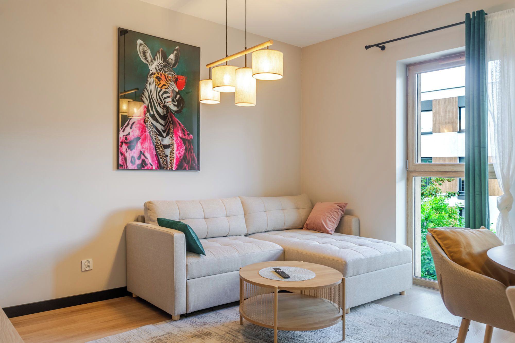 A living room with a sofa, a round coffee table, a painting, and a window with curtains.