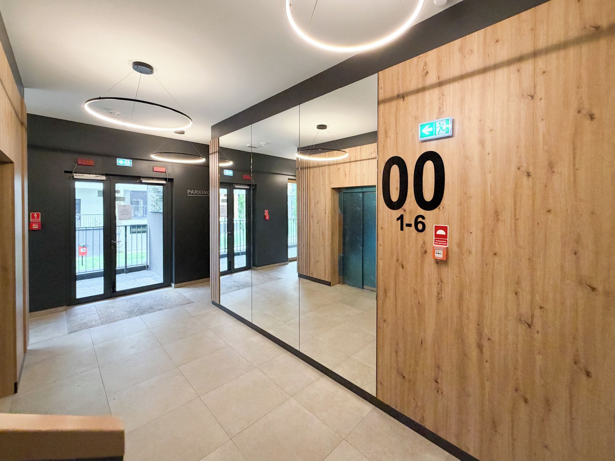 Ein modernes Interieur mit einer Holzwand, einem Spiegelbereich und einem sichtbaren Aufzug.