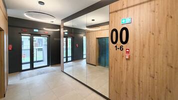 A modern interior with a wooden wall, a mirrored section, and a visible elevator.