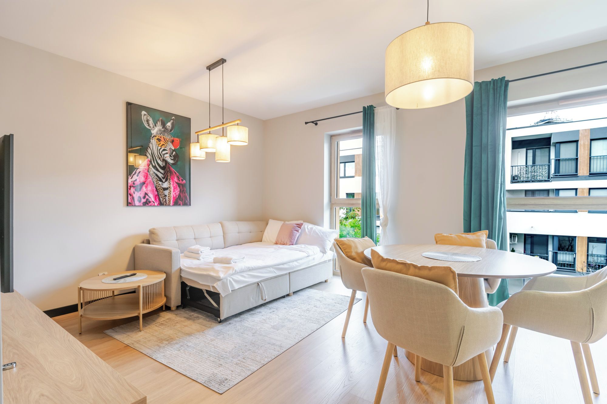 Una sala moderna con un sofá, una mesa de comedor con sillas, un cuadro en la pared y vistas al balcón exterior.