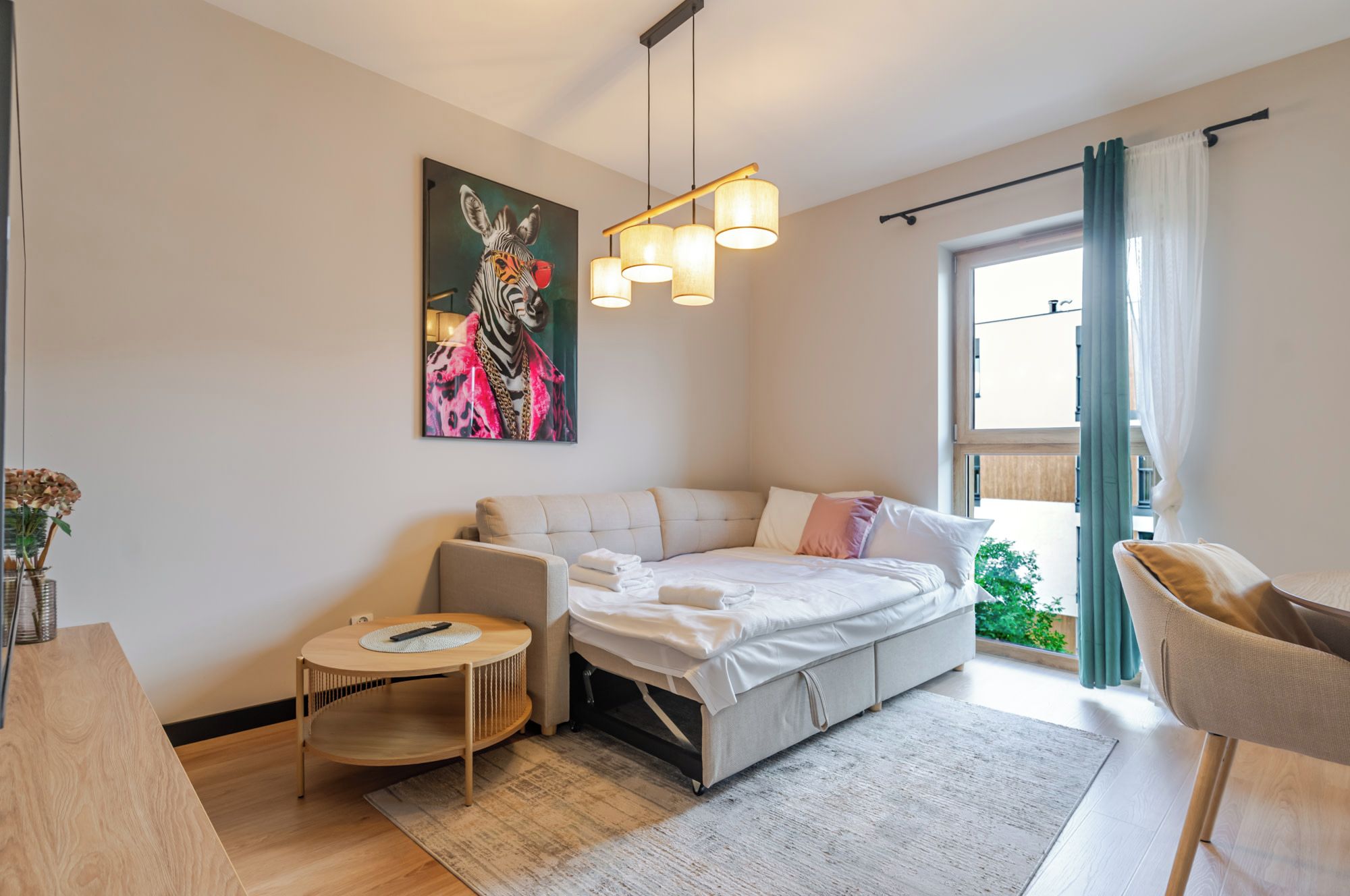 A modern bedroom with a sofa bed, a small round table, and a painting on the wall.