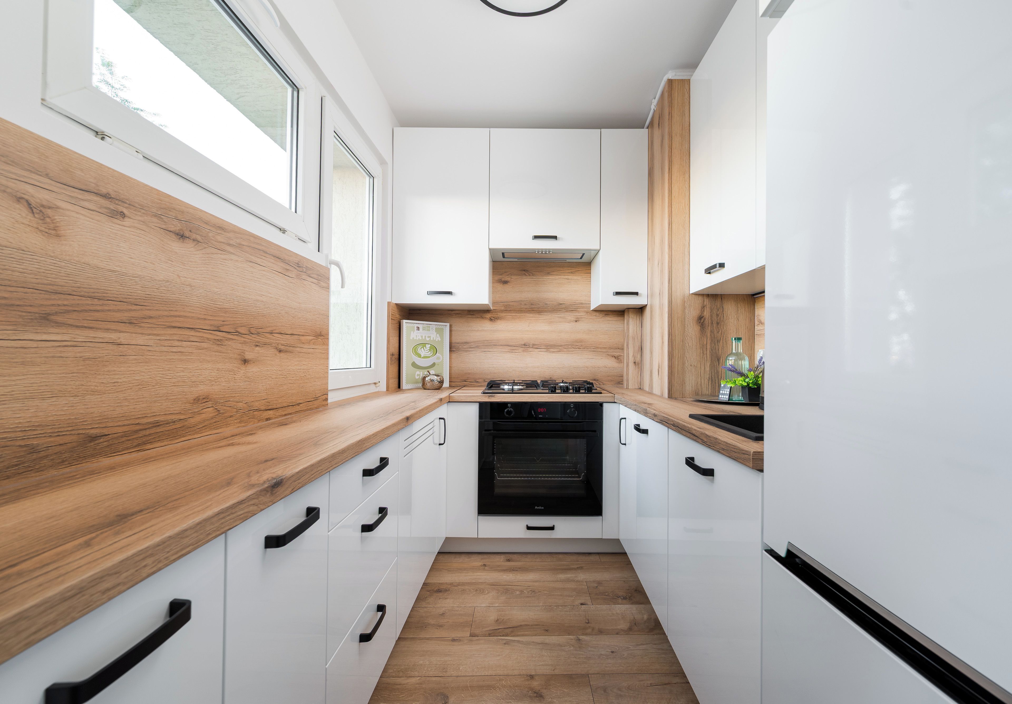 A modern kitchen with white cabinetry, wooden countertops, and a built-in oven.
