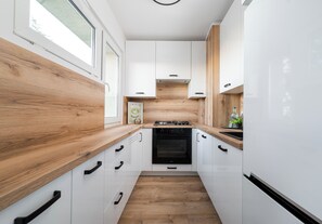 A modern kitchen with white cabinetry, wooden countertops, and a built-in oven. - Mokotów Rzymowskiego Urban Apartment (Warszawa)
