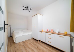 Ein Schlafzimmer mit Bett, Nachttisch, Kleiderschrank und Deckenleuchte.
