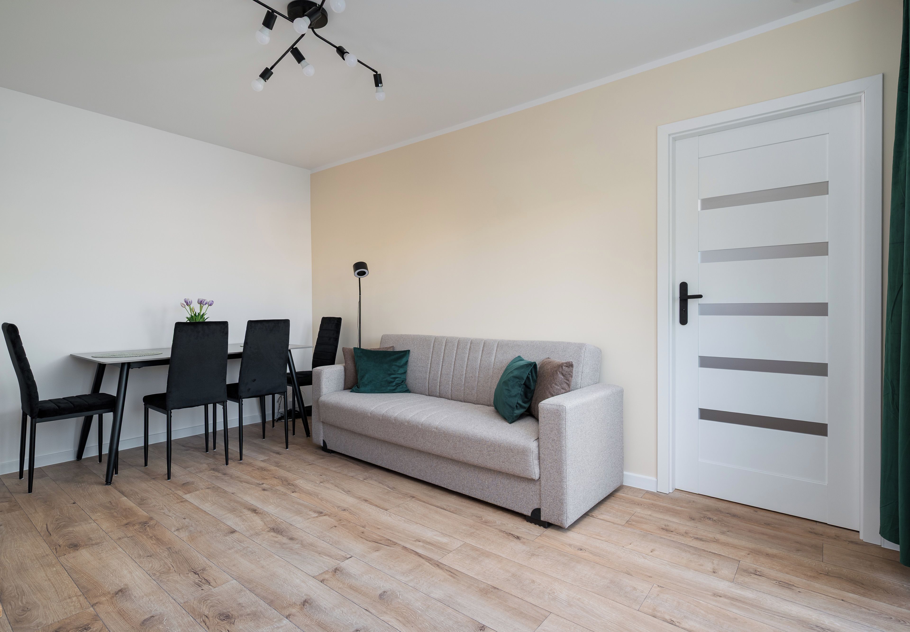 A room with a sofa, chairs, a table, and a door.
