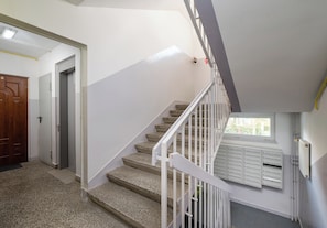 Eine Treppe mit weißen Geländern führt zu einer Zwischenebene mit Briefkästen.