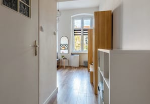 A hallway with a wooden floor, a white door, and a window with a view of the outside. - Piastów Loft Mezzanine Studio (Szczecin)