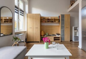 A modern living space with a white table, a green vase with flowers, and a bookshelf. - Piastów Loft Mezzanine Studio (Szczecin)