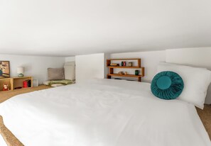 A modern bedroom with a large bed, a wooden nightstand, a bookshelf, and a decorative pillow. - Piastów Loft Mezzanine Studio (Szczecin)