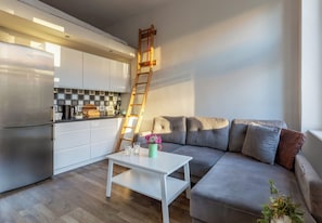 A modern kitchen with white cabinets, a stainless steel refrigerator, and a wooden ladder leaning against the wall. - Piastów Loft Mezzanine Studio (Szczecin)