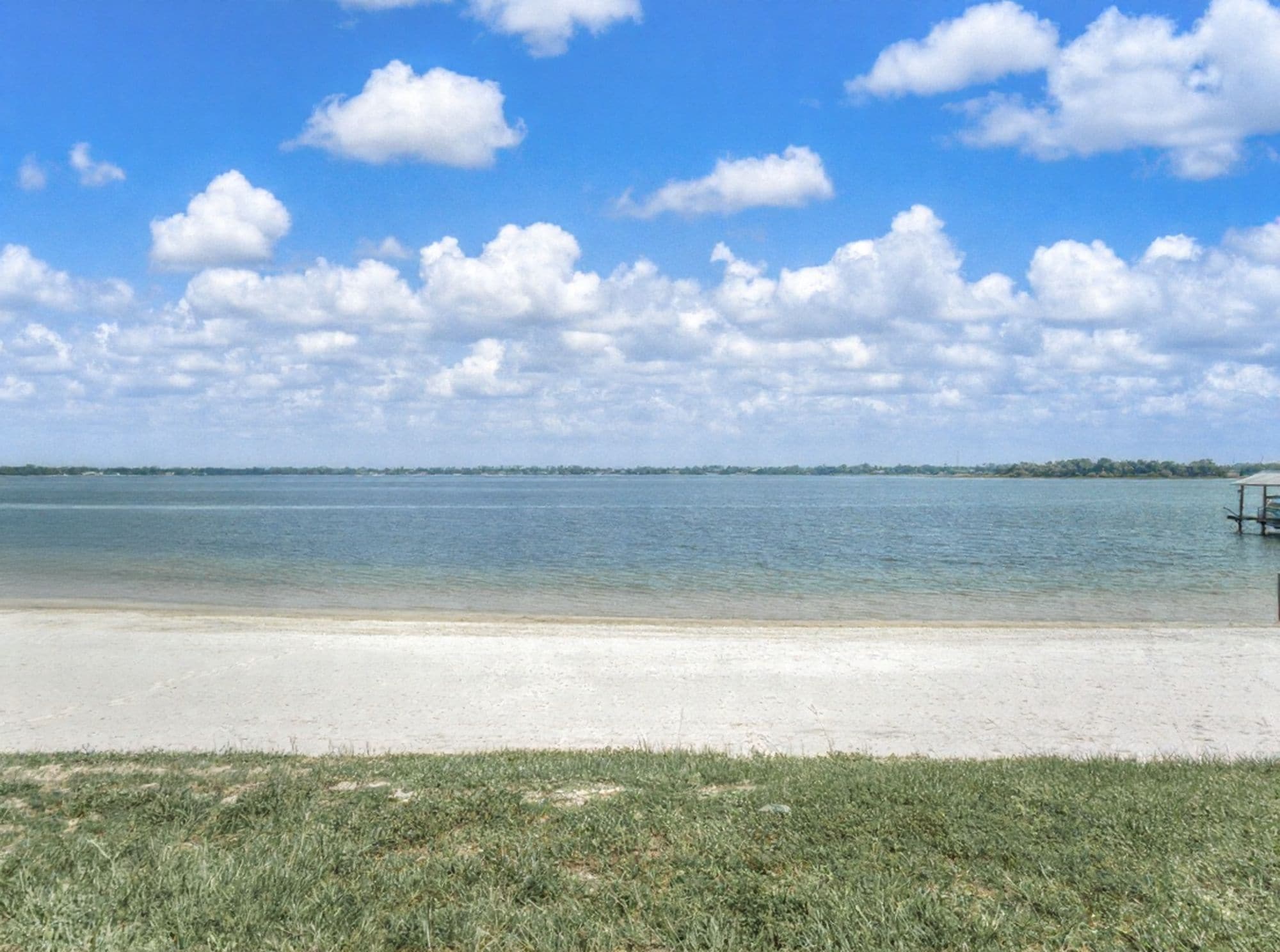 Une plage avec un ciel dégagé et une eau calme.