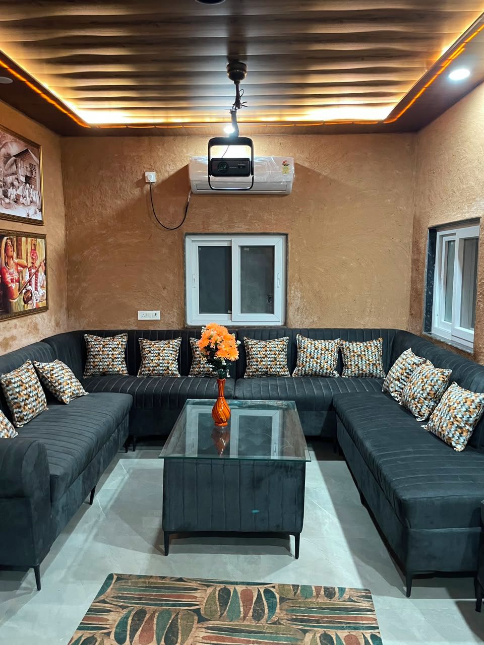 A living room with a sectional sofa, a glass coffee table, and patterned cushions.