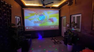 A room with a large screen displaying a presentation, a ceiling fan, and a floor with colorful lights.