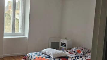 Une chambre à coucher avec un lit, une table de chevet, un ventilateur de plafond et une fenêtre.