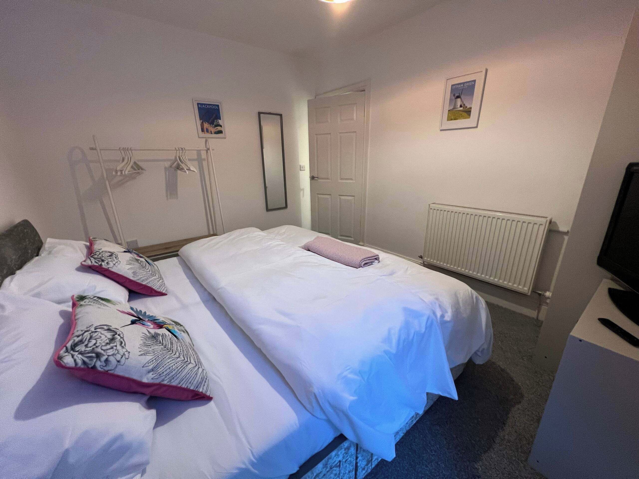 A hotel room with two beds, a radiator, a television, and a framed picture on the wall.
