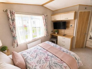 Ein Schlafzimmer mit Bett, Schreibtisch, Fernseher und Kleiderschrank.