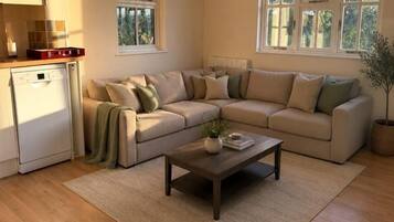 A living room with a beige sectional sofa, a wooden coffee table, a small plant, and a window with a view of trees.