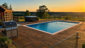 A backyard with a swimming pool, a barbecue grill, and a hot tub.