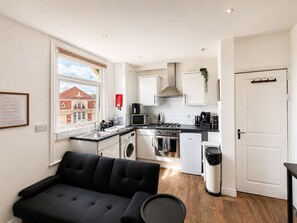 A compact kitchen with a washing machine, a compact fridge, and a microwave. - Apartment - Sleeps 4 - Free Parking (Leeds)