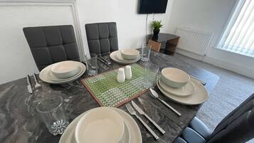 A dining area with a table set for four, including plates, cutlery, and glasses.