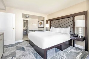 A hotel room with a large bed, a bedside table with a lamp, and a view of the bathroom.