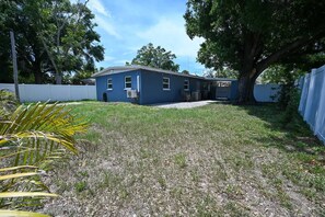 A residential property with a two-story house, a front yard with grass and a tree, and a white fence. - The Grounded Oak | 1mi to UT, Fenced Yard (Tampa)